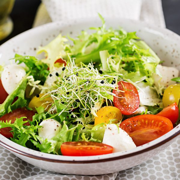 Vegetarian salad with cherry tomato, mozzarella and lettuce. Italian cuisine.